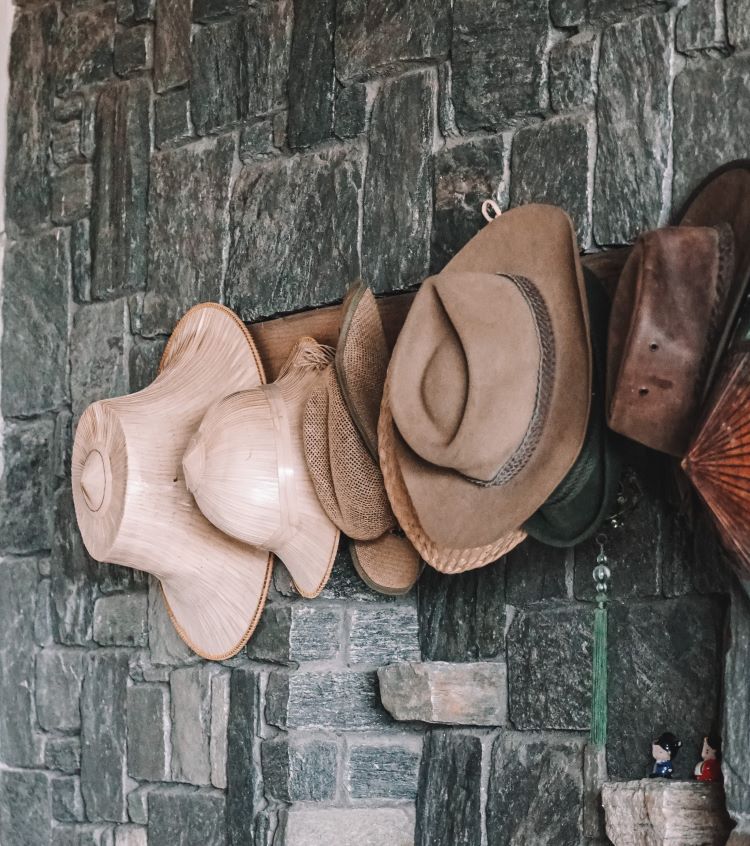 Various hats displayed on a stone wall.
